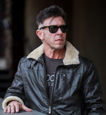 man with dark hair, leather jacket, and sunglasses
