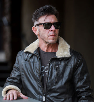 man with dark hair, leather jacket, and sunglasses